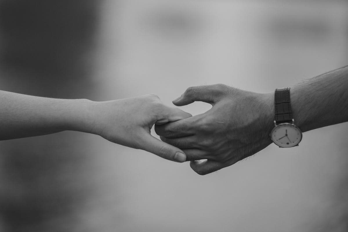서로의 손을 잡고 있는 커플의 흑백 사진, 애착유형에 따라 달라지는 관계 패턴과 유대감을 상징